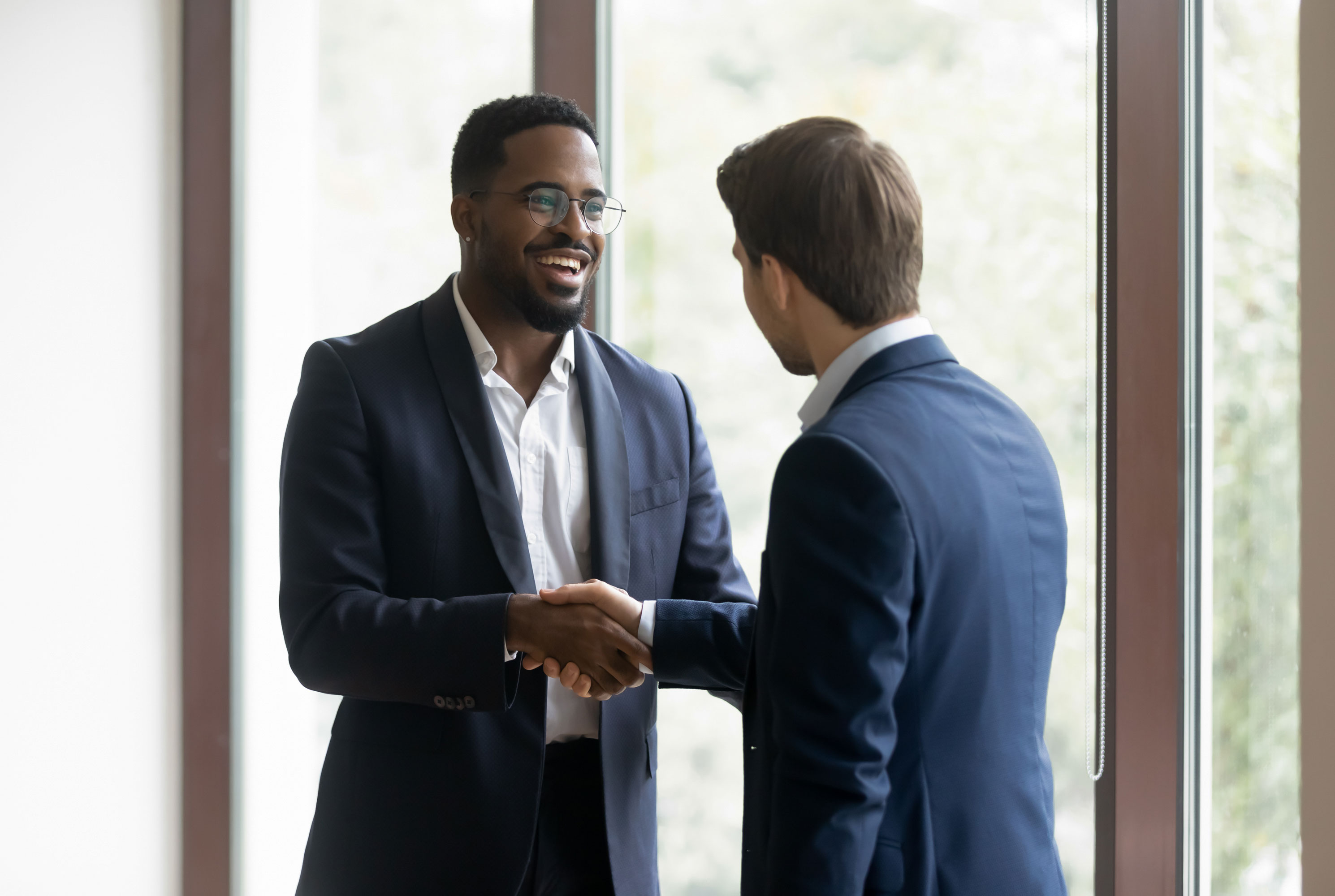 Overjoyed-multiethnic-businessmen-shake-hands